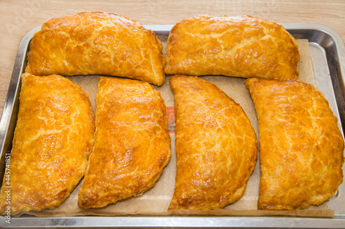 Baked puff pastry with delicious yellow cheese on a metal tray. Bakery products national traditional dishes and pastries.