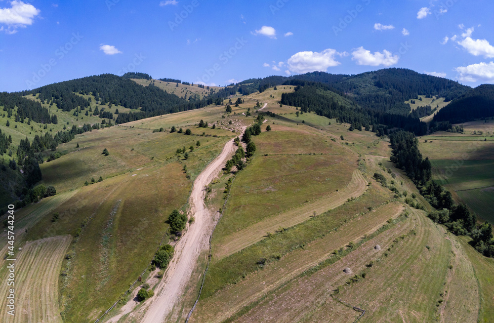 Dirt road leading to the top of the mountain aerial drone view in Transylvania, Romania.