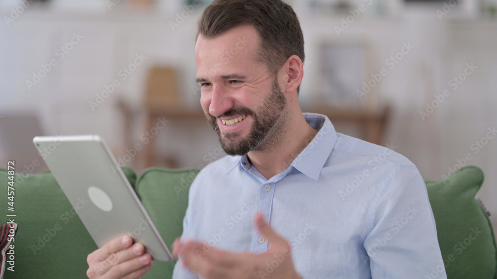 Young Man Celebrating Success on Tablet Young Man Celebrating Success on Tablet