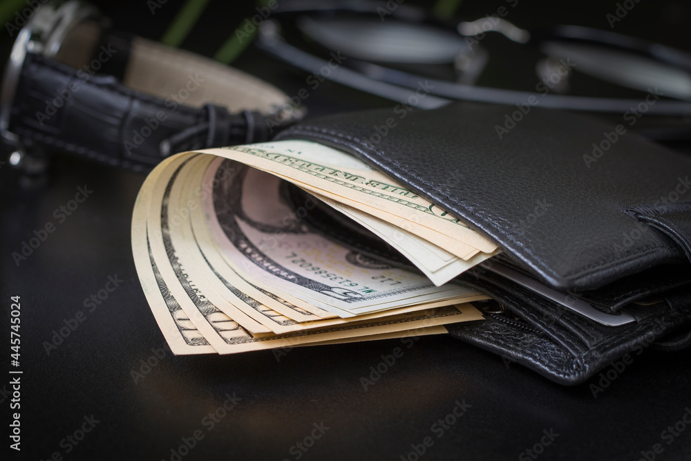Dollar bills in a wallet and on a dark background.