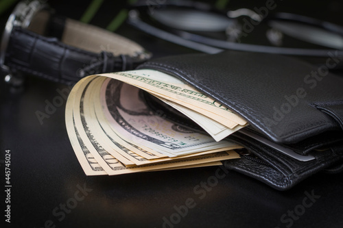Dollar bills in a wallet and on a dark background.