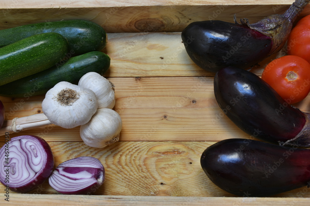 vassoio in legno grezzo con sopra melanzane,
pomodori, aglio, zucchine e cipolla. Ingredienti della cucina tipica siciliana, Vegano
