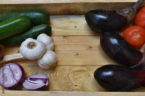 Obraz na płótnie vassoio in legno grezzo con sopra melanzane,
pomodori, aglio, zucchine e cipolla. Ingredienti della cucina tipica siciliana, Vegano w salonie