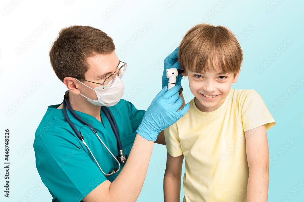 Pediatric pediatrician man examines the ears of the child with an otoscope in the clinic. The boy smiles. White background Pediatric pediatrician man examines the ears of the child with an otoscope in the clinic. The boy smiles. White background