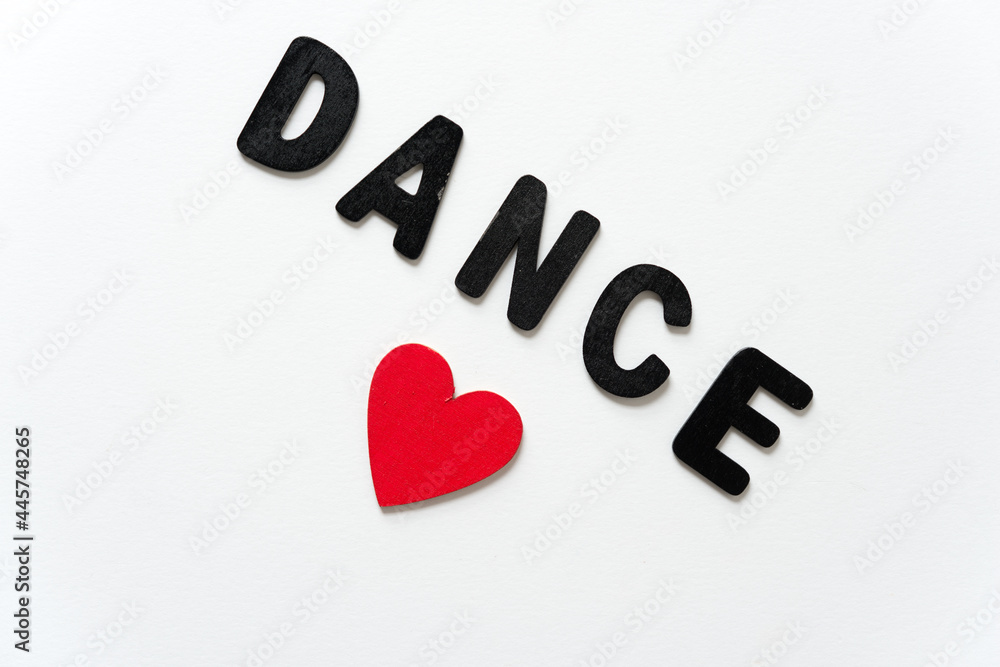 sign with the word dance in all caps in black chalk letters with a hand painted wooden heart on a white background