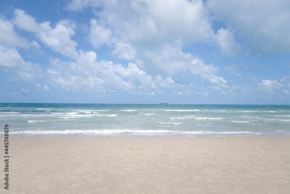 Beautiful natural scene of tropical summer sand beach with blue sea and cloudy sky, ocean waves crashing on beach island.