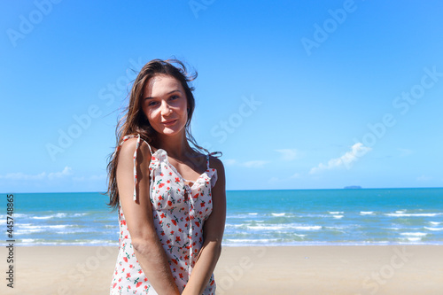 Portrait of smiling young beautiful woman with blond long hair standing on tropical blue sea summer beach, relaxing vacation summer concept.