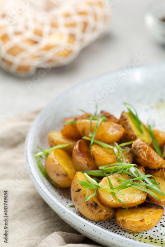Potato wedges, oven roasted close up on light concrete background. Roasted baby potatoes. fries potatoes with green onions.