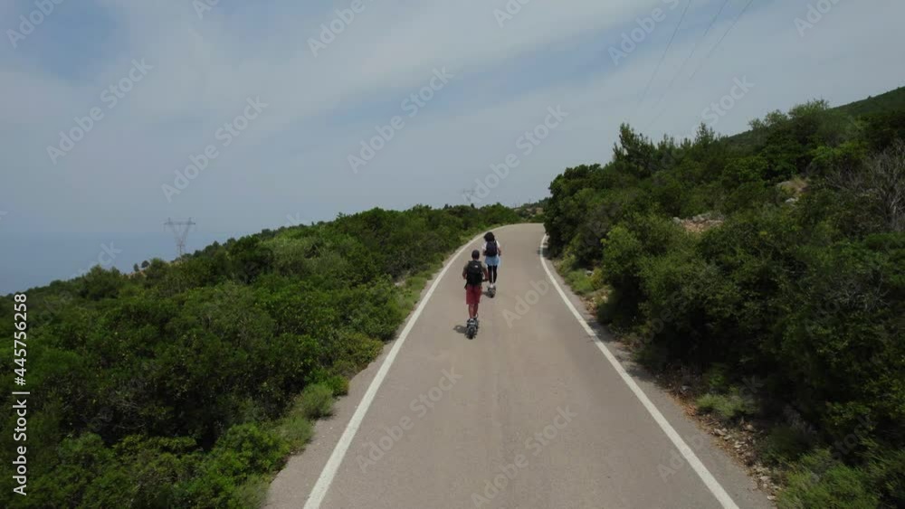 Man and Woman on the Electric Scooter Aerial Follow Scene in the forest by the sea 4K UHD Aerial Drone Shot. Man and Woman on the Electric Scooter Aerial Follow Scene in the forest by the sea 4K UHD Aerial Drone Shot.