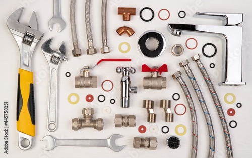 Quadro su tela Plumber tools and spare parts on white wooden background, top view, flat lay