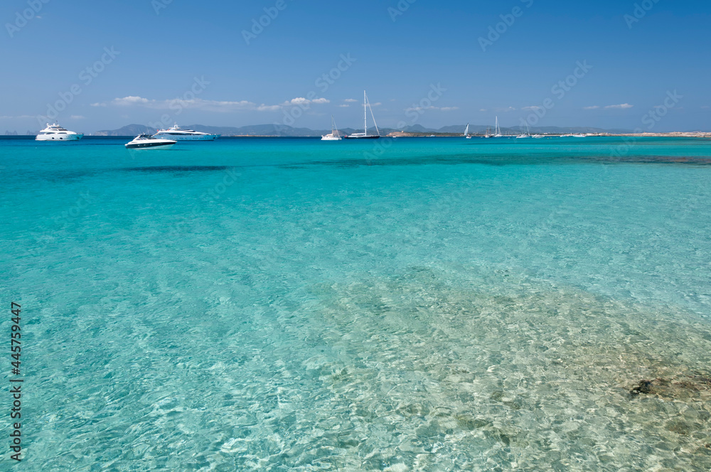 Panoramic view of Ses Illetes beach, Formentera, Spain. In the background, luxury boats anchored. Concept travel and tourism
