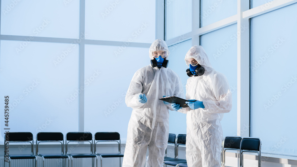 lab technicians in protective suits discussing the work plan. lab technicians in protective suits discussing the work plan.