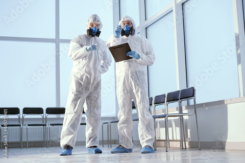 researchers in protective suits discussing something standing in the lab. © yurolaitsalbert