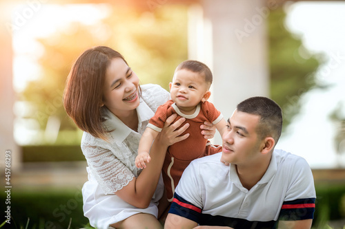 Happy young Asian family spending time outdoor the summer holiday. Happy young family spend time outdoor in garden during the summer holiday. Happy family, life insurance, stability in life concept.
