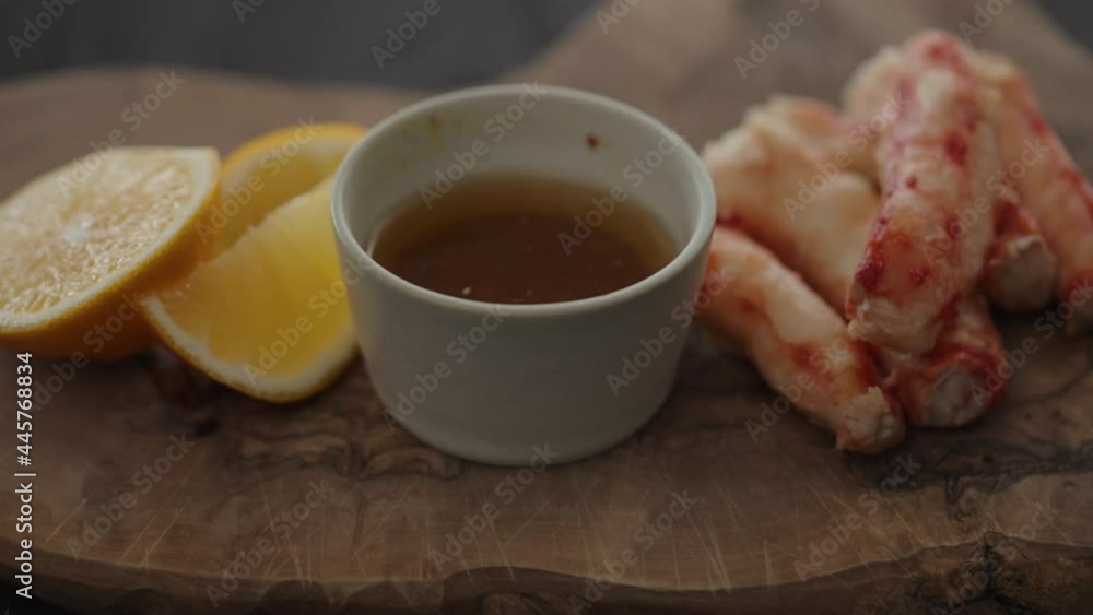 Slow motion gimbal shot of crab leg meat on a olive board with sweet lemon and dip sauce Slow motion gimbal shot of crab leg meat on a olive board with sweet lemon and dip sauce