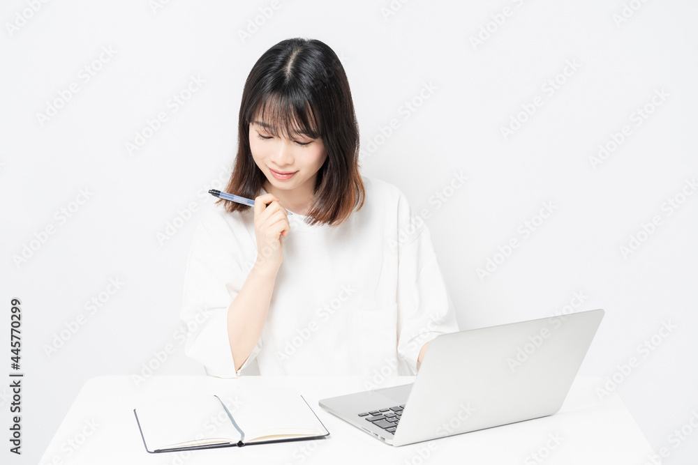 白背景の前でノートパソコンを使う若い女性 白背景の前でノートパソコンを使う若い女性