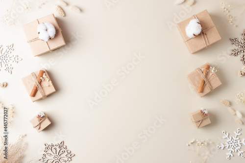 Christmas decorations with packaging gifts in craft paper and flowers on beige background. Zero waste Christmas holiday concept. Flat lay, copy space