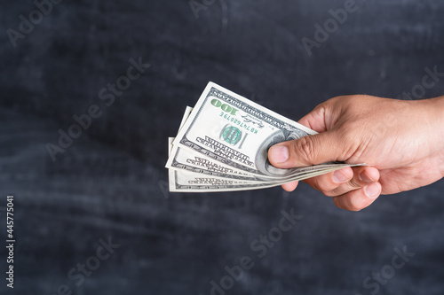 Fotografija Male hand with dollars on a dark background, the concept of corruption and bribery