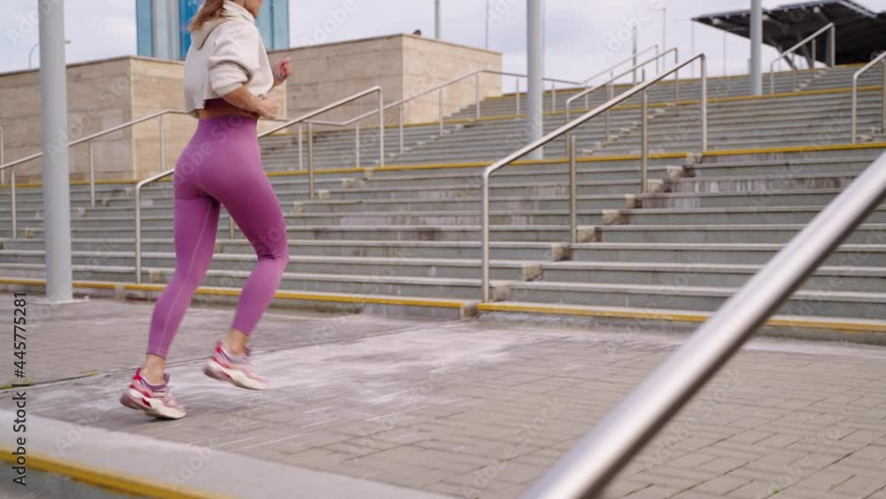 outdoors training in city, woman is running over stairs, tensing legs muscles outdoors training in city, woman is running over stairs, tensing legs muscles