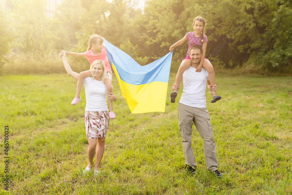 Fototapeta premium Flag Ukraine in hands of little girl in field. Child carries fluttering blue and yellow flag of Ukraine against background field.
