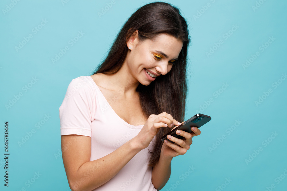 Pretty girl with smartphone in hands addicted to social media. Portrait of smiling young woman browsing on telephone. Female expresses joyful emotions. Pretty girl with smartphone in hands addicted to social media. Portrait of smiling young woman browsing on telephone. Female expresses joyful emotions.