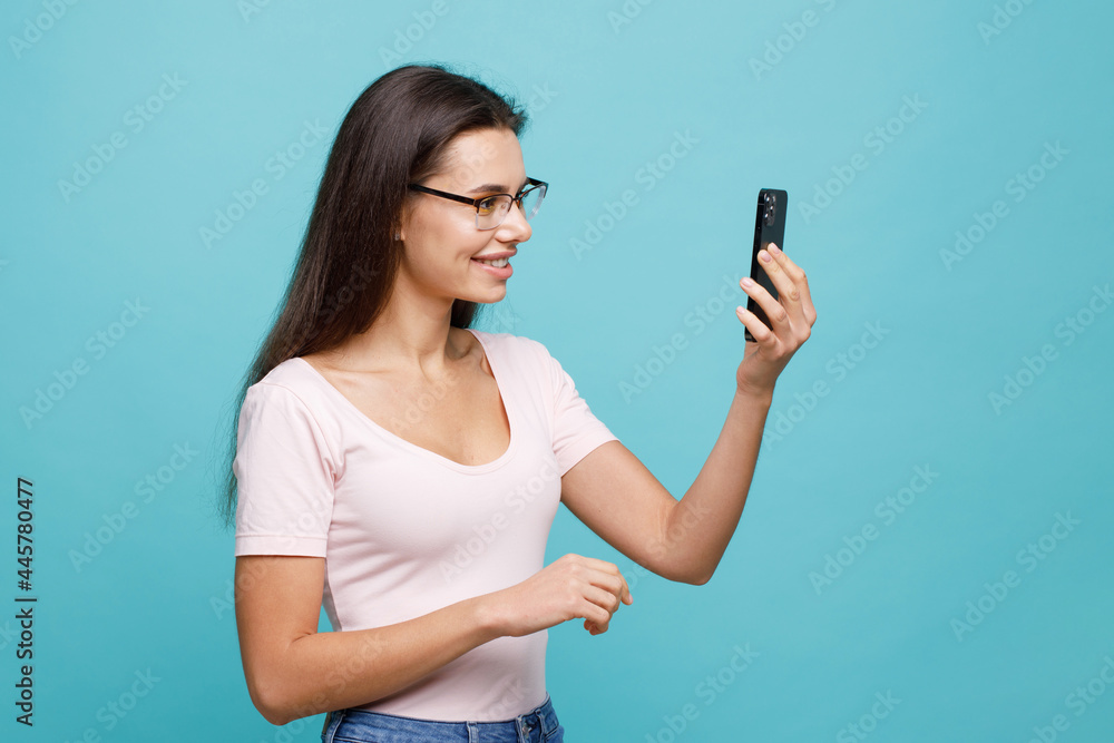 Pretty girl with smartphone in hands. Smiling young woman taking selfie. Blogger influencer looking at camera make video conference call recordin. Female expresses happiness.