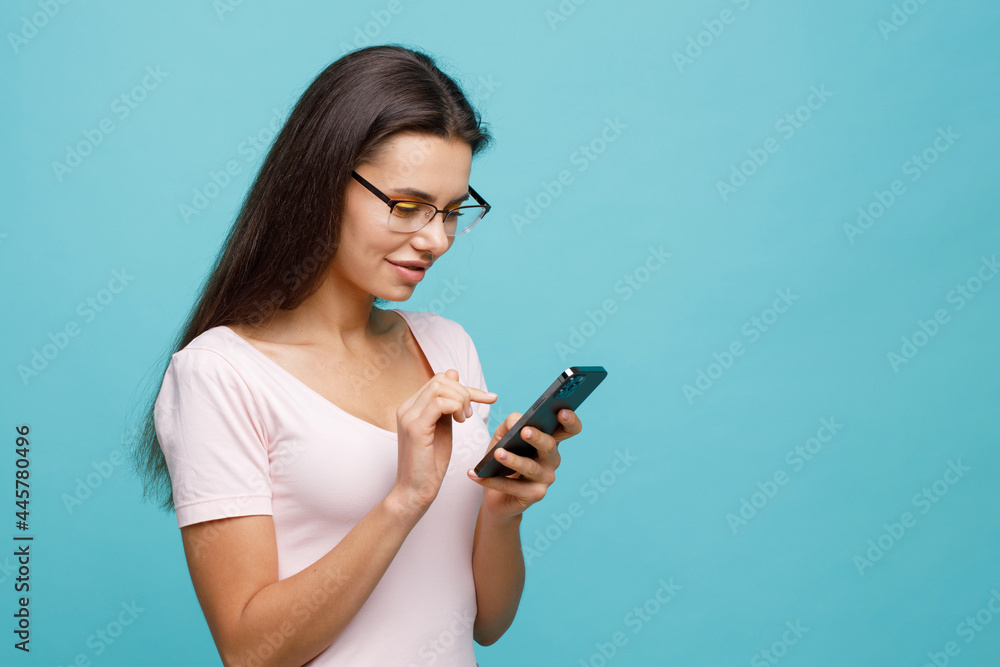 Pretty girl with smartphone in hands addicted to social media. Portrait of smiling young woman browsing on telephone. Female expresses joyful emotions. Pretty girl with smartphone in hands addicted to social media. Portrait of smiling young woman browsing on telephone. Female expresses joyful emotions.