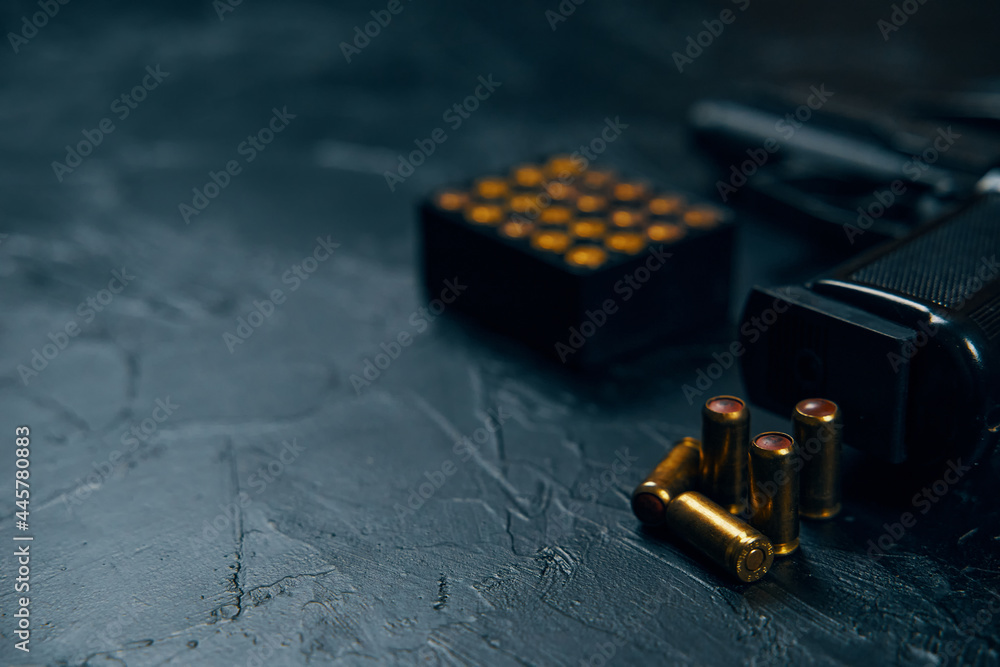 Close-up of gun handle and bullets on concrete table. Firearms and ammunition. Concept of defense or attack. Copy space for text. Close-up of gun handle and bullets on concrete table. Firearms and ammunition. Concept of defense or attack. Copy space for text.