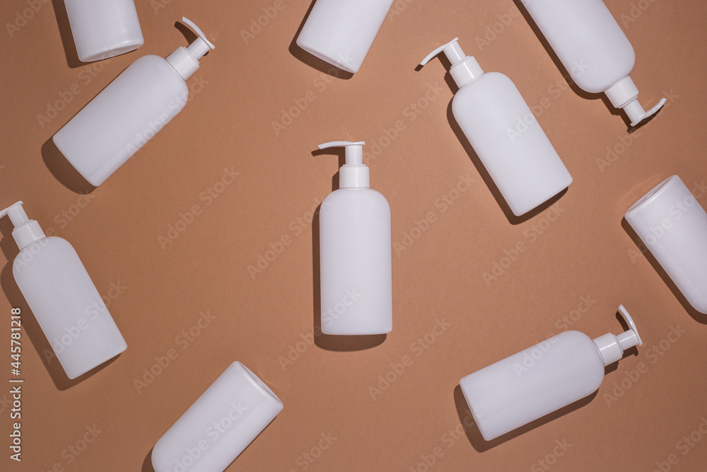 White bottles with a dispenser lie on a brown cardboard background. Top view, flat lay White bottles with a dispenser lie on a brown cardboard background. Top view, flat lay