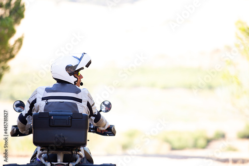 Tableau sur toile Vista trasera de motorista llevando casco abierto con fondo claro