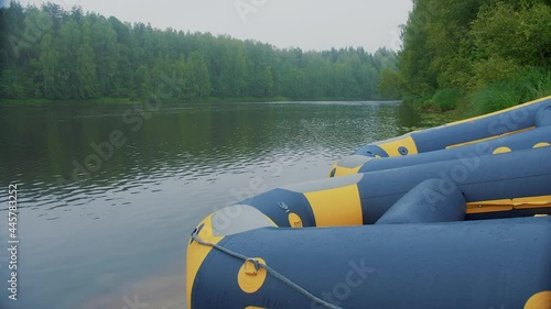 Slow motion. Boats for rafting, kayaking, canoes, kayaks are located on the river bank. A wide, fast river, cloudy weather. The boats are ready to depart.