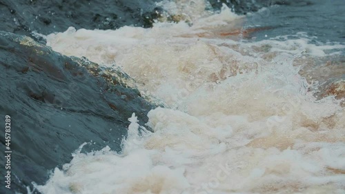 Strong flow of water with splashes and foam in slow motion. Powerful raging river flow. Extreme steep river threshold. Emergency water discharge. Dam break, spring flood, dangerous weather conditions.