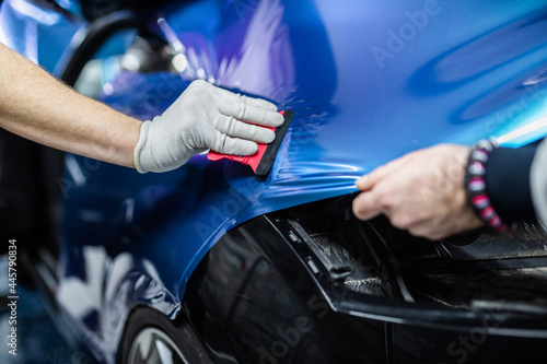 Car wrapping specialists putting vinyl foil or film on car. Selective focus. © hedgehog94