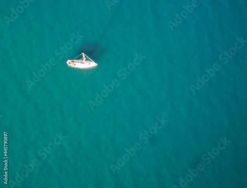 An aerial view of a sailboat with a blue ocean background.  © phillips