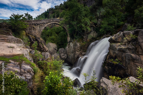 View of the ancient Mizarela Bridge or Devil’s Bridge with a waterfall, over Rabagao river, at the Peneda Geres National Park, in Portugal, Europe photo