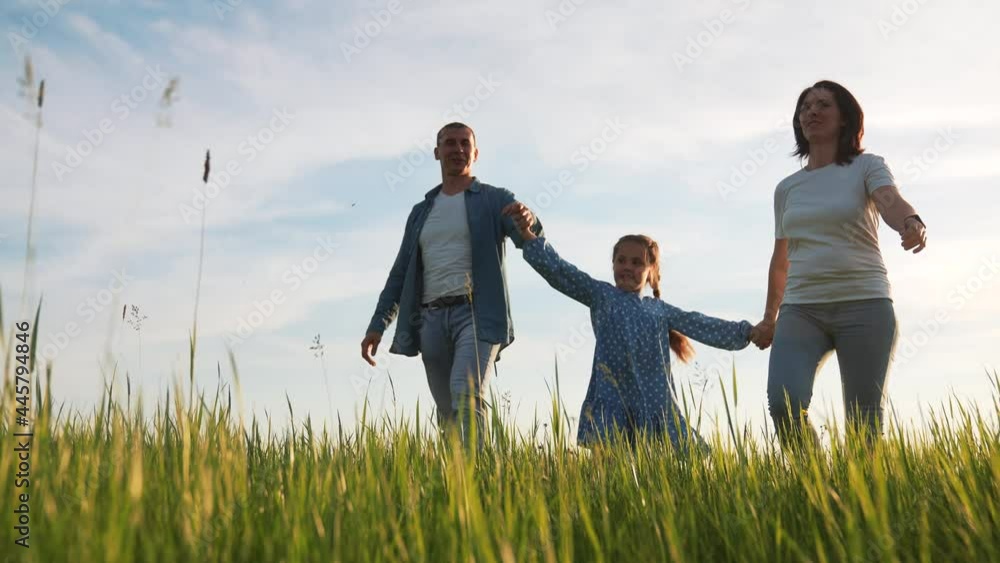 Happy cute family. Happy dream people in park. Parents and daughter hiking on green grass. Concept of happy family. Parents and daughter walk on green grass. Family hiking. Dream baby in park Happy cute family. Happy dream people in park. Parents and daughter hiking on green grass. Concept of happy family. Parents and daughter walk on green grass. Family hiking. Dream baby in park