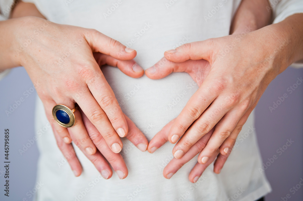 Happy Couple Waiting a Baby. Parents Hands on the Belly of the Pregnant Mother.