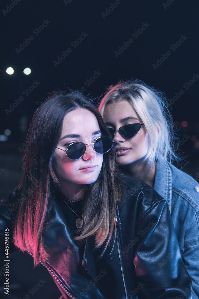 a couple of girls in love on a motorbike in the rays of neon light in an empty parking lot at night a couple of girls in love on a motorbike in the rays of neon light in an empty parking lot at night
