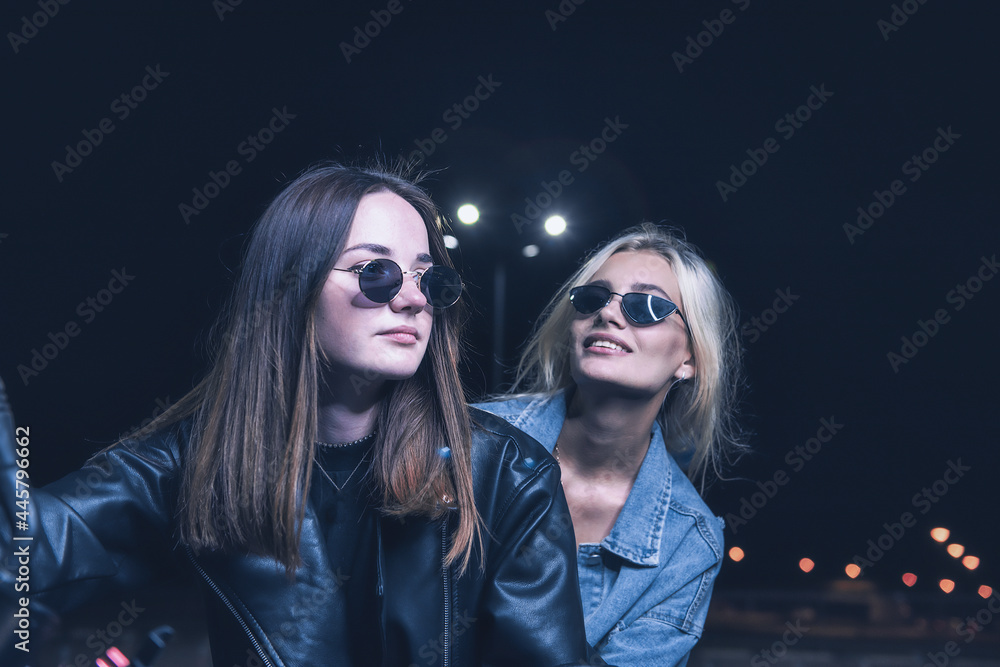 a couple of girls in love on a motorbike in the rays of neon light in an empty parking lot at night a couple of girls in love on a motorbike in the rays of neon light in an empty parking lot at night
