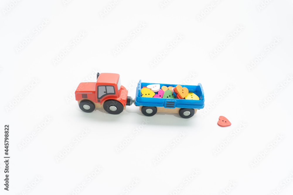 Creative concept of small red tractor toy, blue trailer toy and colorful hearts. Creative concept of small red tractor toy, blue trailer toy and colorful hearts.
