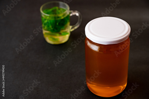 Jar of honey with a cup of tea