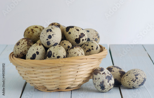 Quail Eggs in a basket over a light blue wooden table. Isolated in white background