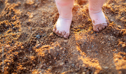 Children's bare feet in summer on a golden sandy beach close-up. The concept of child safety. The concept of recreation with children.