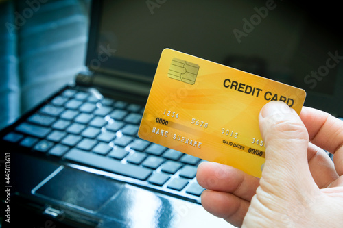 Young man sat in the living room on the sofa holding his credit card.soft focus