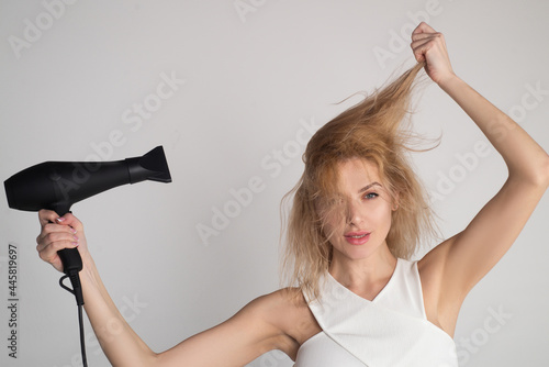 Woman touching her hair. Girl with blonde hair using hairdryer. Hairstyle, hairdressing concept.