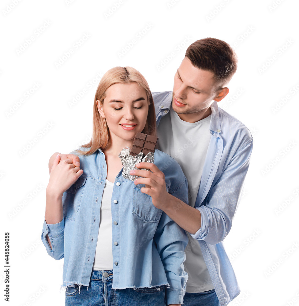 Young couple eating tasty chocolate on white background Young couple eating tasty chocolate on white background