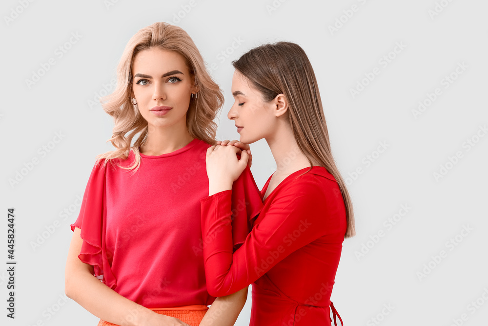 Beautiful young sisters on light background Beautiful young sisters on light background