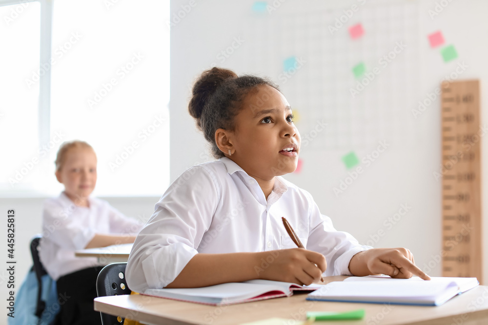 Cute African-American girl during lesson at school Cute African-American girl during lesson at school