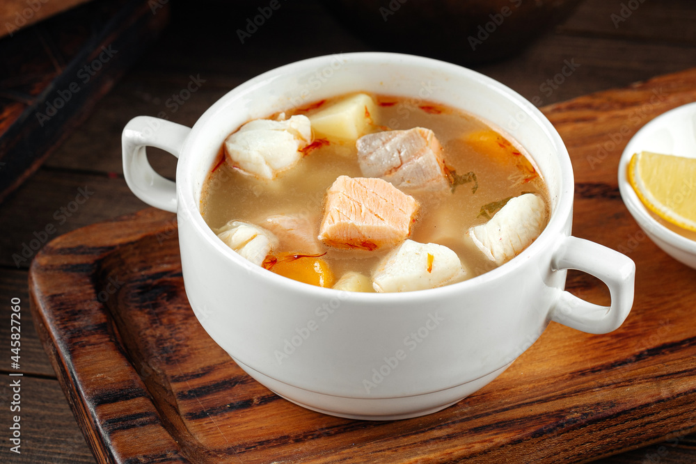 Bowl of ukha fish soup with lemon on the wooden background Bowl of ukha fish soup with lemon on the wooden background