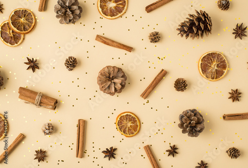 Top view photo of scattered pine cones anise dried lemon slices cinnamon sticks and golden sequins on isolated light beige background